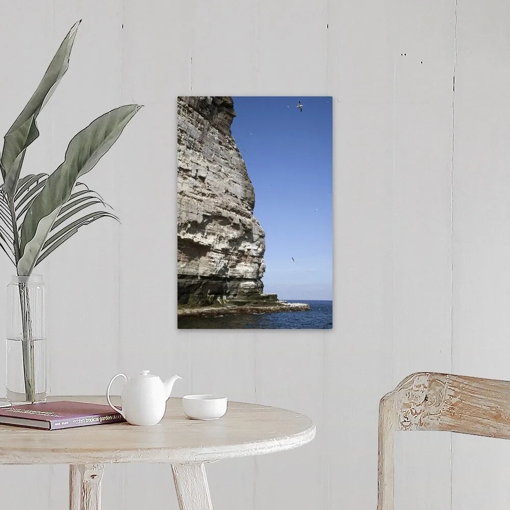 "a tall rock face on the water's edge" Canvas Wall Art