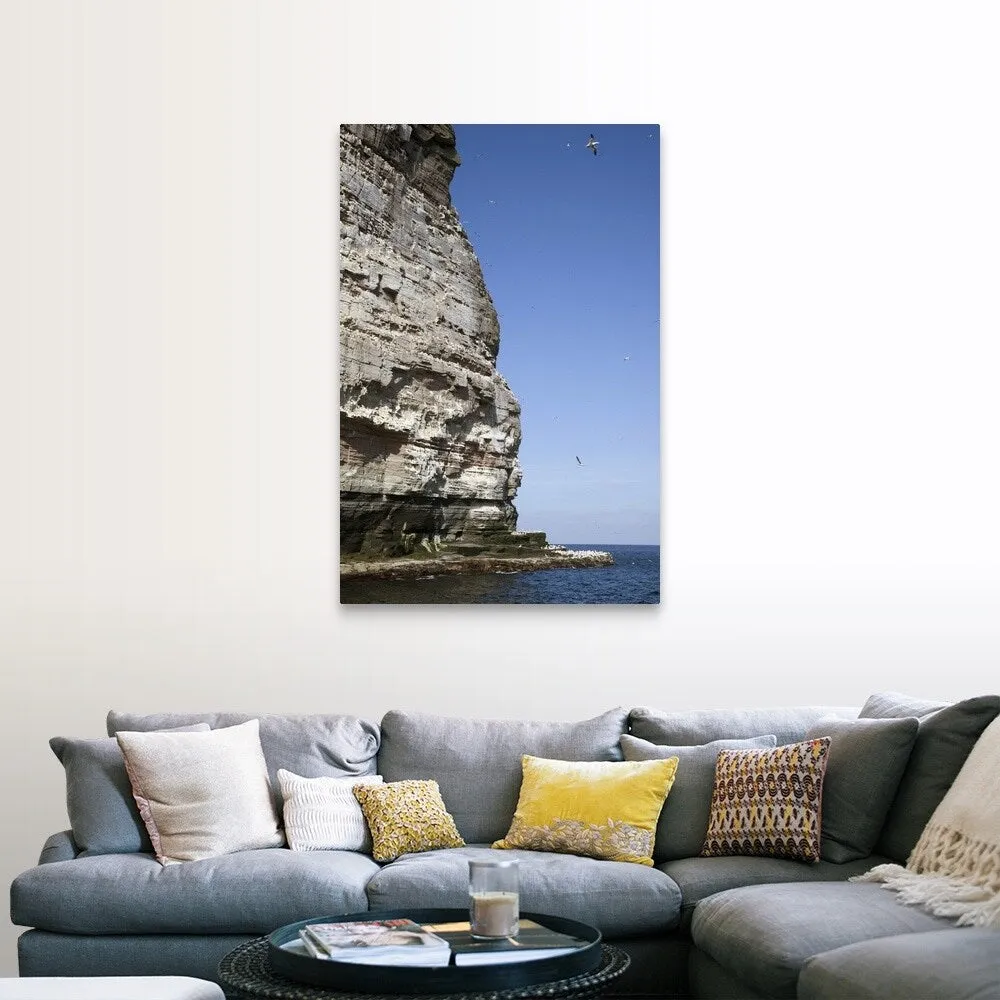 "a tall rock face on the water's edge" Canvas Wall Art